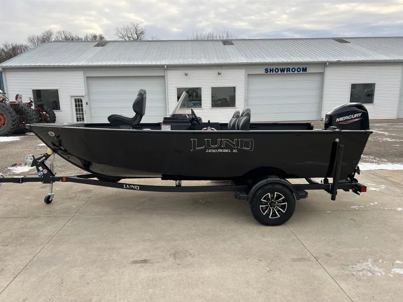 Slide: The Image of 2025 Lund 1650 Rebel XL SS Blackout boat on trailer outside showroom. - 3