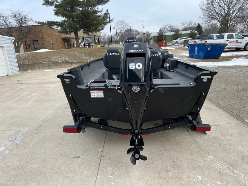 Slide: The Image of 2025 Lund 1650 Rebel XL SS Blackout boat with Mercury 60 engine, parked outdoors. - 5