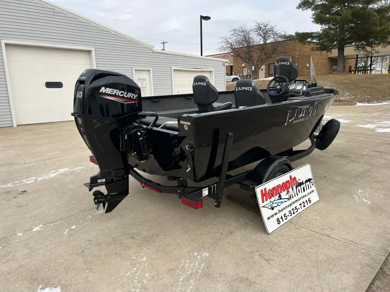 Slide: The Image of 2025 Lund 1650 Rebel XL SS Blackout boat with Mercury engine, parked outdoors. - 6