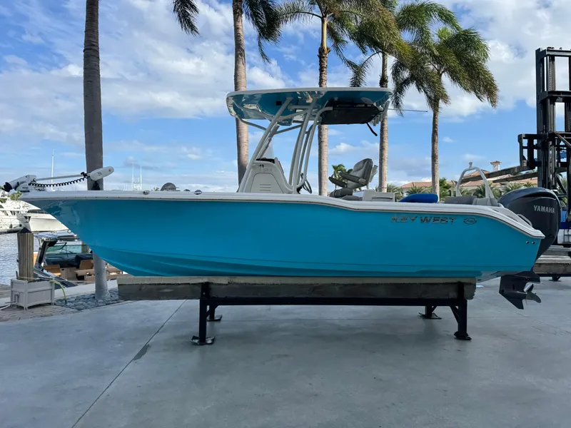 Slide: The Image of 2024 Key West 239 FS boat in vibrant blue, docked with palm trees in the background. - 1