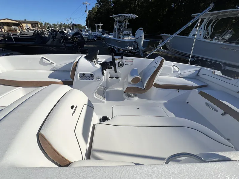 Slide: The Image of 2025 Stingray SC 182SC boat interior with white and brown seating, docked among other boats. - 5