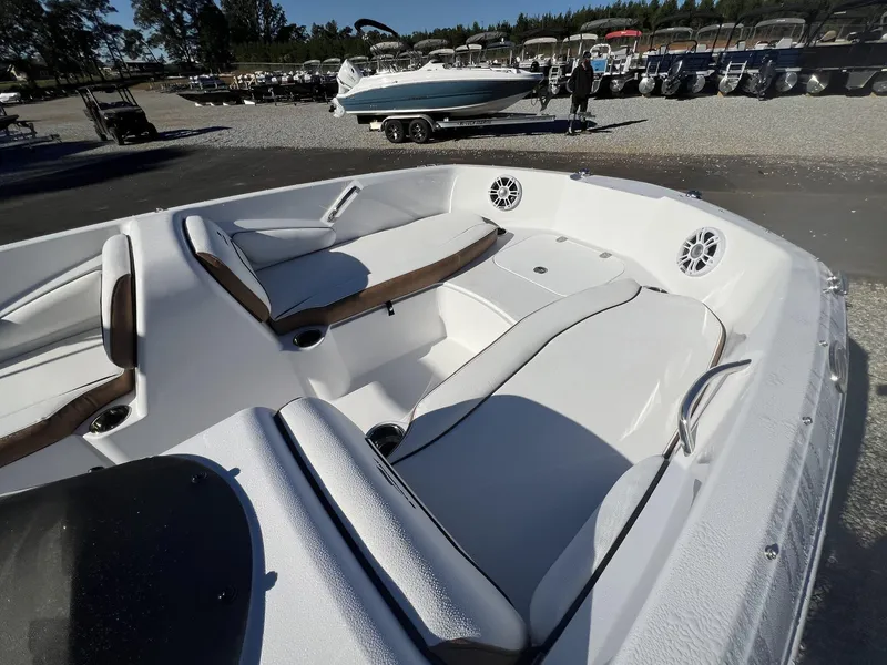 Slide: The Image of 2025 Stingray SC 182SC boat interior with white seating and speakers, parked outdoors. - 6
