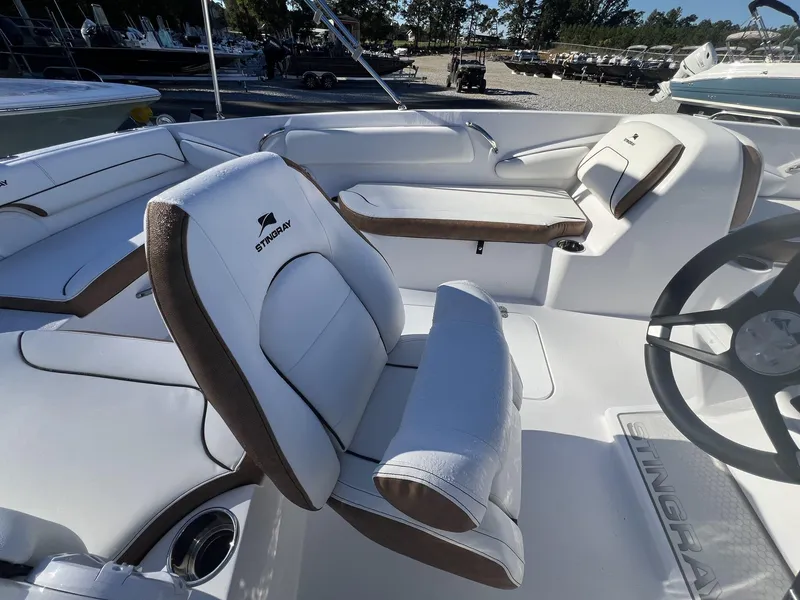 Slide: The Image of 2025 Stingray SC 182SC boat interior with white and brown seating, steering wheel, and logo. - 8
