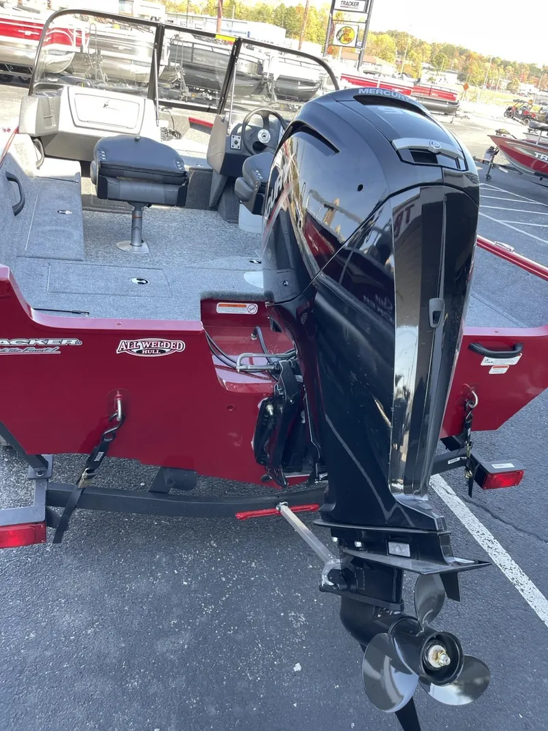Slide: The Image of 2025 Tracker Pro Guide V-16 WT boat with powerful outboard motor in a parking lot. - 3