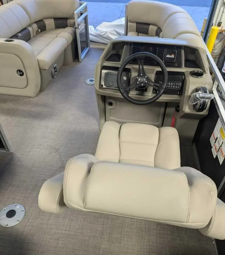 Slide: The Image of 2025 Sun Tracker Party Barge 22 RF DLX interior with beige seating and steering console. - 3