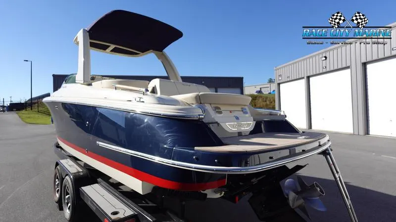 Slide: The Image of 2025 Chris-Craft 28GT boat on trailer, blue and white exterior, parked near storage units. - 6
