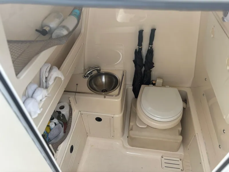 Slide: The Image of 2013 Scout 275 LXF boat bathroom with sink, toilet, and storage shelves. - 19