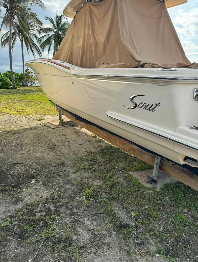 Slide: The Image of 2013 Scout 275 LXF boat on land, covered, with palm trees in background. - 3