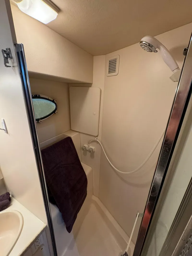 Slide: The Image of 1989 Sea Ray 39 yacht bathroom with shower, towel, and porthole window. - 17
