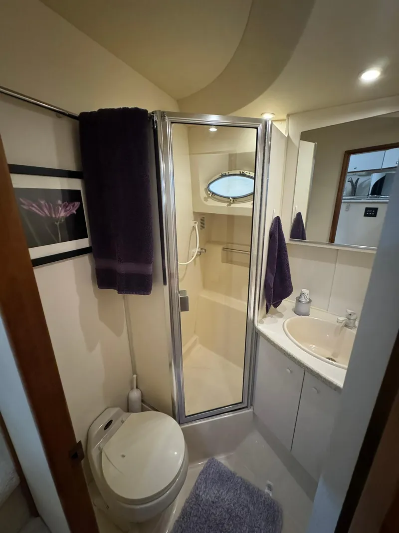 Slide: The Image of 1989 Sea Ray 39 yacht bathroom with shower, sink, and toilet, featuring purple towels and decor. - 22