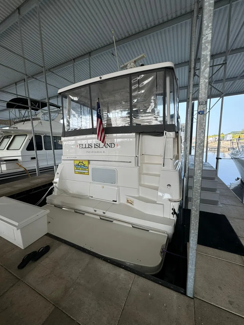 Slide: The Image of 1989 Sea Ray 39 boat docked, featuring an American flag and covered deck area. - 31