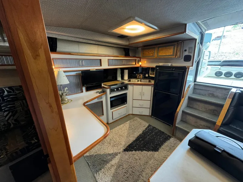 Slide: The Image of Interior of a 1989 Sea Ray 39 boat featuring a compact kitchen and cozy seating area. - 46