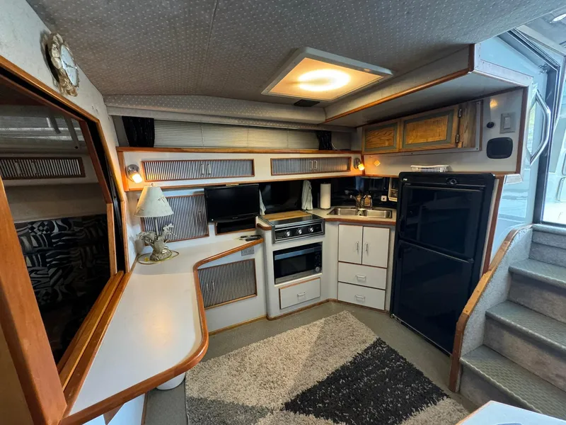 Slide: The Image of 1989 Sea Ray 39 yacht interior with kitchen, stove, fridge, and cozy seating area. - 47