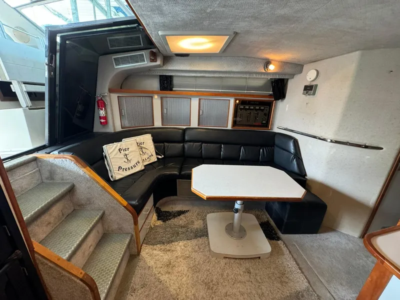 Slide: The Image of 1989 Sea Ray 39 interior with black leather seating, table, and stairs. - 48