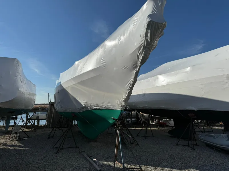 Slide: The Image of 1998 Island Packet 40 sailboat, shrink-wrapped, stored on land, clear sky background. - 14