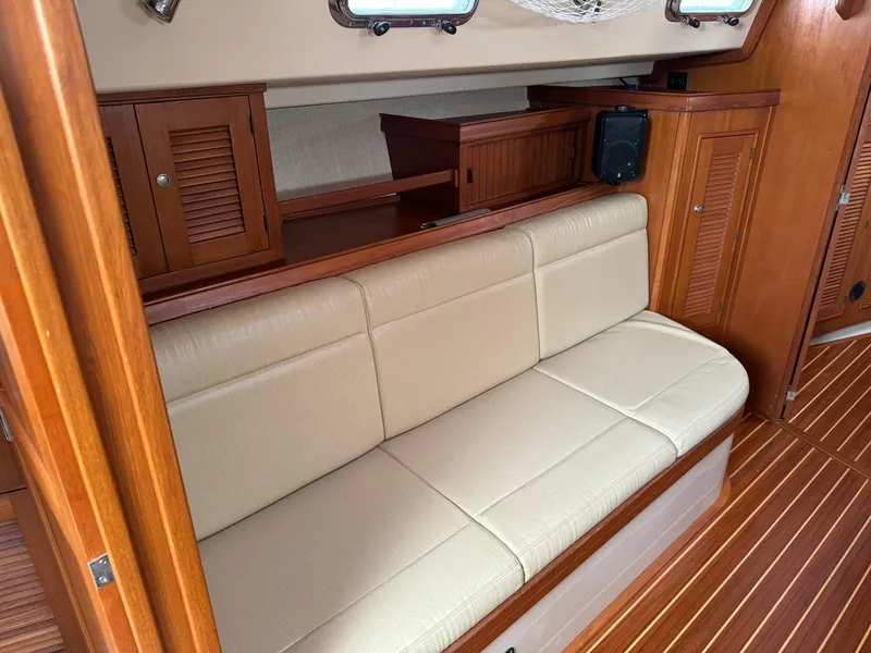 Slide: The Image of Interior of 1998 Island Packet 40 sailboat with beige seating and wooden cabinetry. - 23