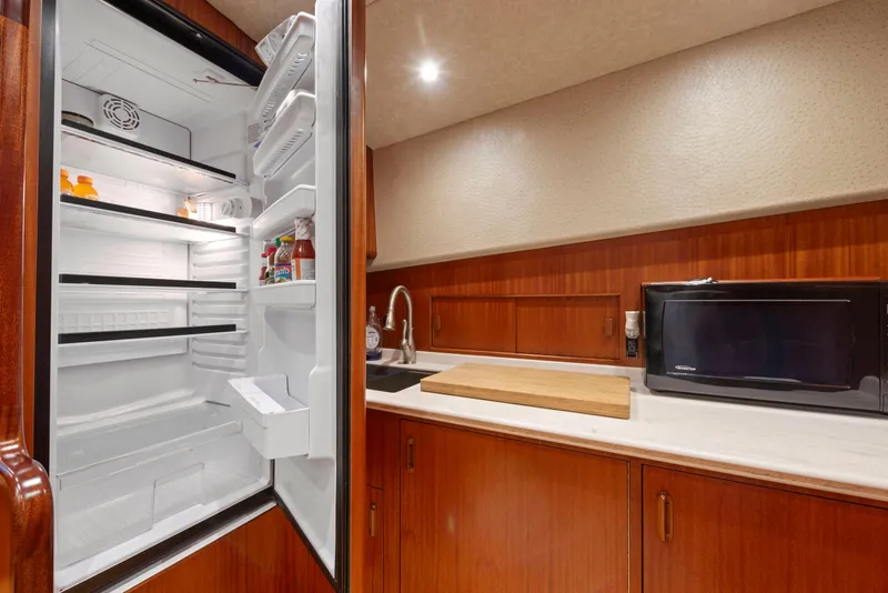 Slide: The Image of 1963 Whiticar 54 Sportfisherman kitchen with open fridge, microwave, and wooden cabinetry. - 36