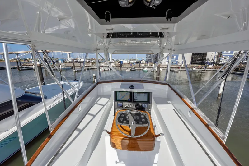 Slide: The Image of 1963 Whiticar 54 Sportfisherman helm with marina view, featuring classic wooden steering wheel. - 9