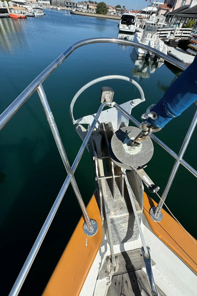 Slide: The Image of 1984 Transpacific Marine Ketch bow with anchor, docked in a serene marina. - 12