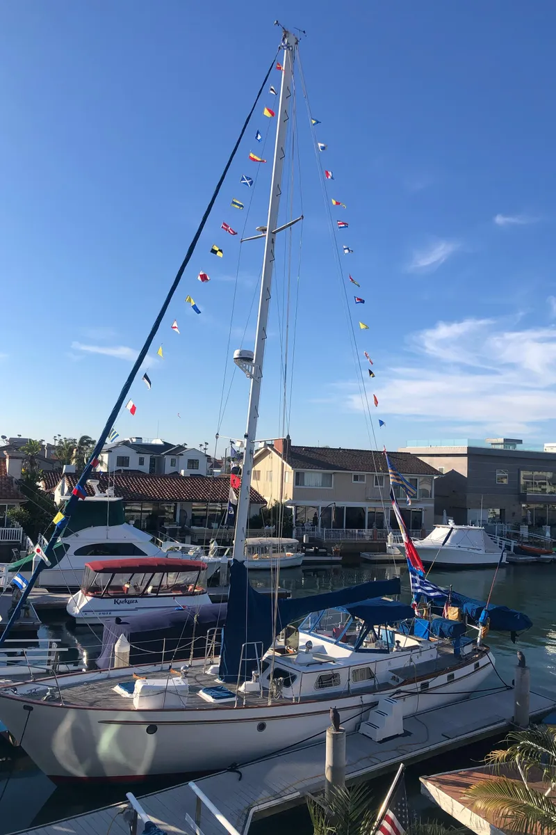 Slide: The Image of 1984 Transpacific Marine Ketch docked, adorned with colorful flags, under a clear blue sky. - 2