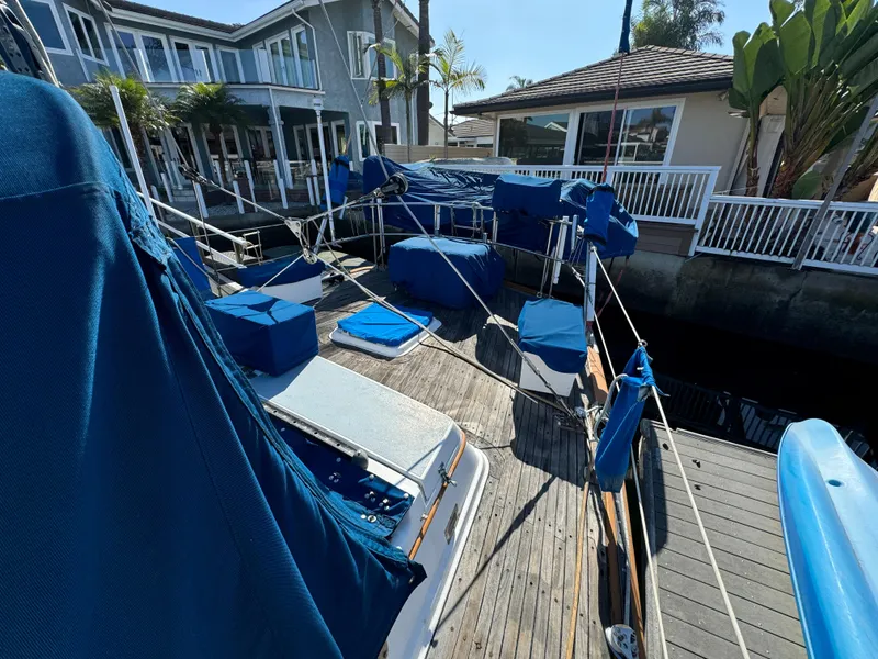 Slide: The Image of 1984 Transpacific Marine Ketch docked, covered in blue tarps, near waterfront homes. - 22