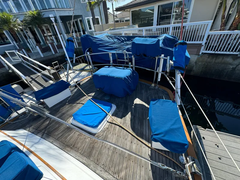 Slide: The Image of 1984 Transpacific Marine Ketch with blue covers docked near waterfront homes. - 23