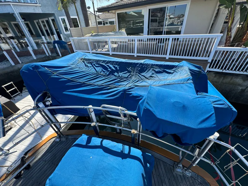 Slide: The Image of 1984 Transpacific Marine Ketch with blue covers docked near waterfront homes. - 25