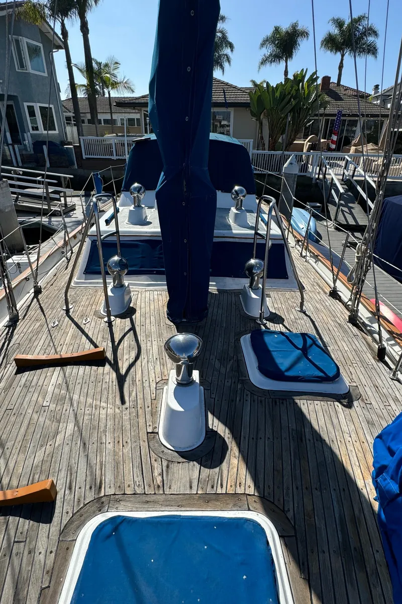 Slide: The Image of 1984 Transpacific Marine Ketch deck with winches and blue covers, docked near palm trees. - 27