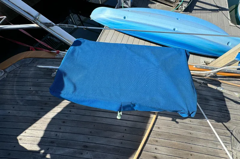 Slide: The Image of 1984 Transpacific Marine Ketch deck with blue cover and wooden planks. - 28