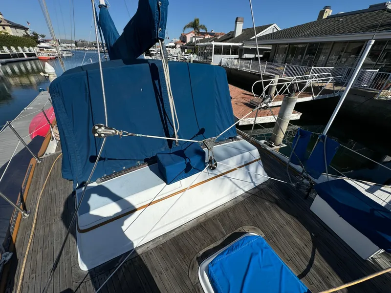 Slide: The Image of 1984 Transpacific Marine Ketch with blue covers docked at a marina. - 30