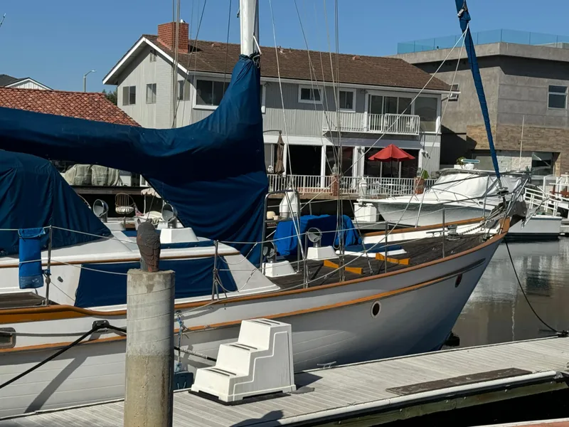 Slide: The Image of 1984 Transpacific Marine Ketch docked at marina, with residential backdrop. - 5