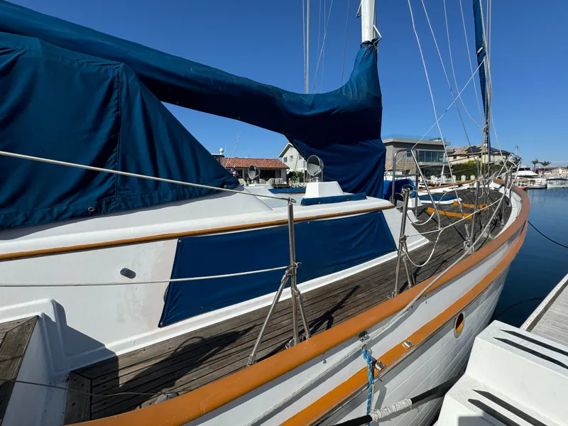 Slide: The Image of 1984 Transpacific Marine Ketch sailboat docked, featuring blue covers and wooden deck. - 8