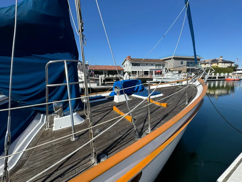 Slide: The Image of 1984 Transpacific Marine Ketch docked at a marina, showcasing its wooden deck and blue sail cover. - 9
