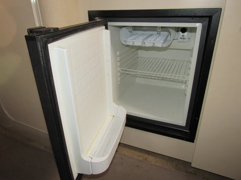 Slide: The Image of Open refrigerator inside 2003 Cruisers Yachts 2870 Express, showcasing interior shelves. - 49