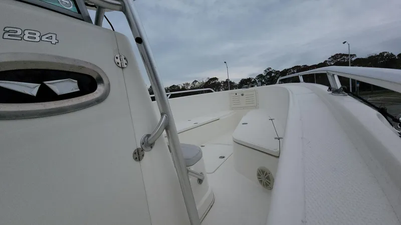 Slide: The Image of 2019 Mako 284 CC boat interior with seating and storage, under cloudy sky. - 13