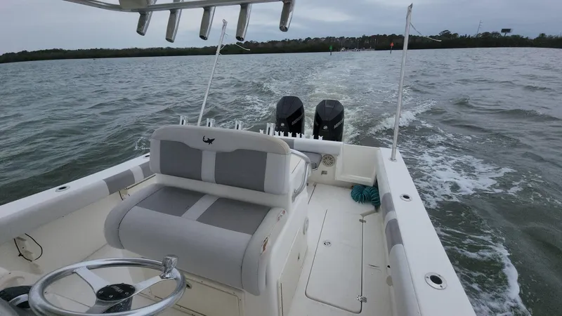 Slide: The Image of 2019 Mako 284 CC boat cruising on open water, featuring dual engines and spacious seating. - 9