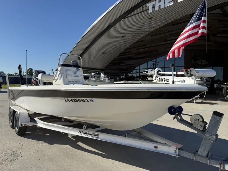 Slide: The Image of 2013 NauticStar 2200 T boat on trailer with American flag, parked outside dealership. - 12