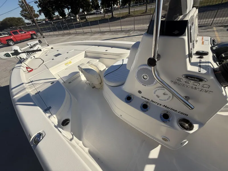 Slide: The Image of 2013 NauticStar 2200 T boat interior with seating and controls, parked outdoors. - 6