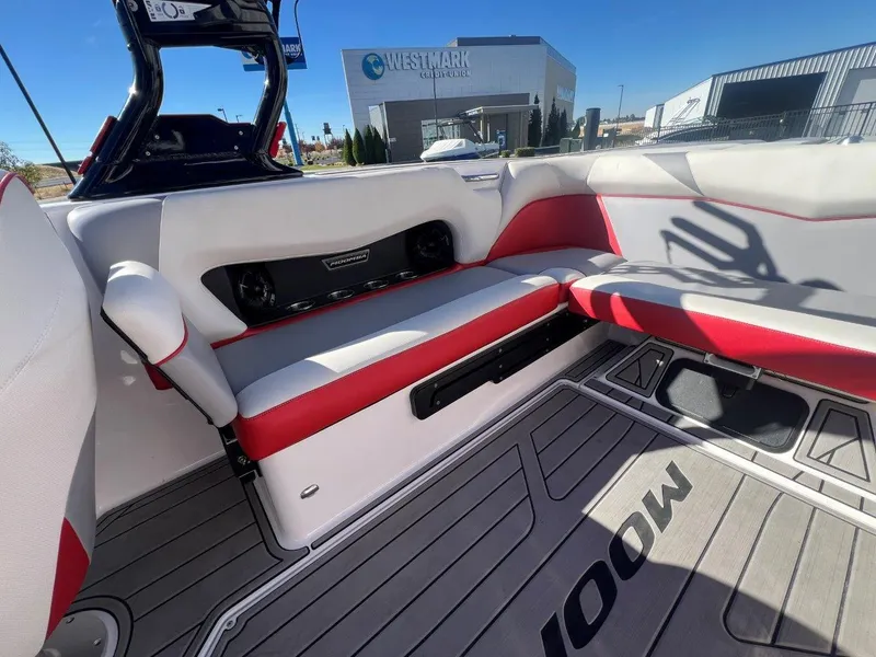 Slide: The Image of 2019 Moomba Mojo boat interior with red and white seating, gray flooring, and speaker system. - 14