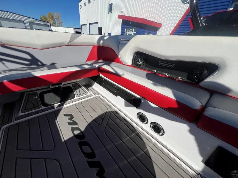 Slide: The Image of 2019 Moomba Mojo boat interior with red and gray seating, speakers, and branded flooring. - 15