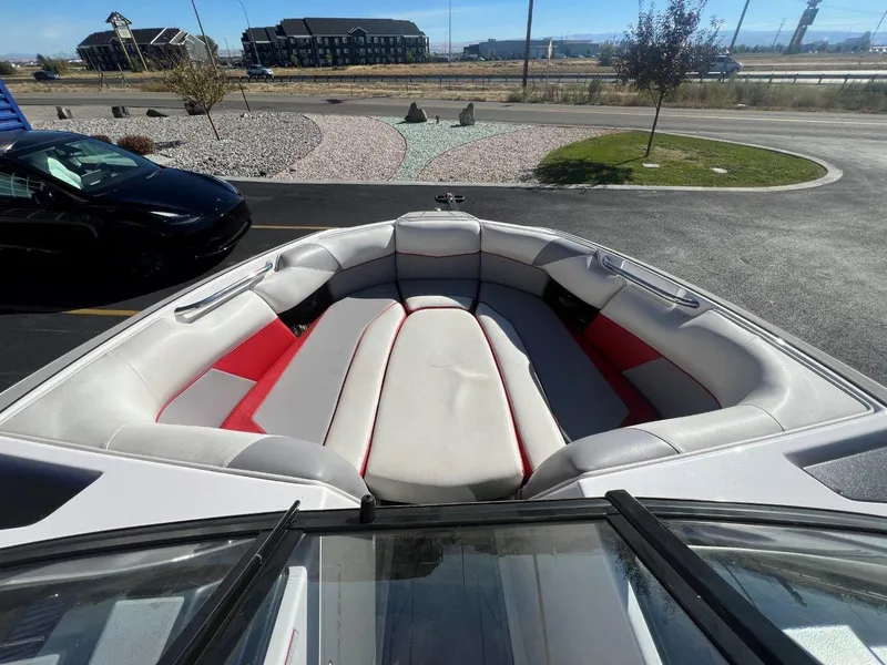 Slide: The Image of 2019 Moomba Mojo boat interior with gray and red seating, parked outdoors. - 16