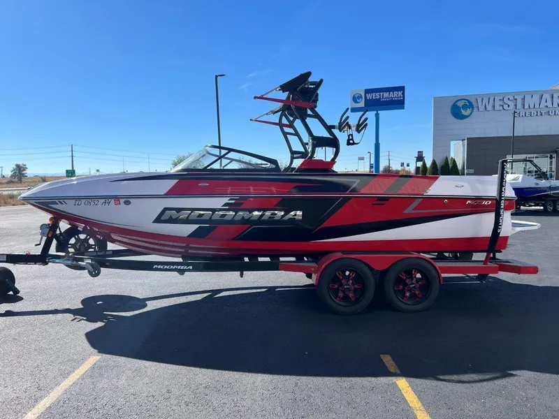 Slide: The Image of 2019 Moomba Mojo boat on trailer, red and white design, parked at Westmark Credit Union. - 7