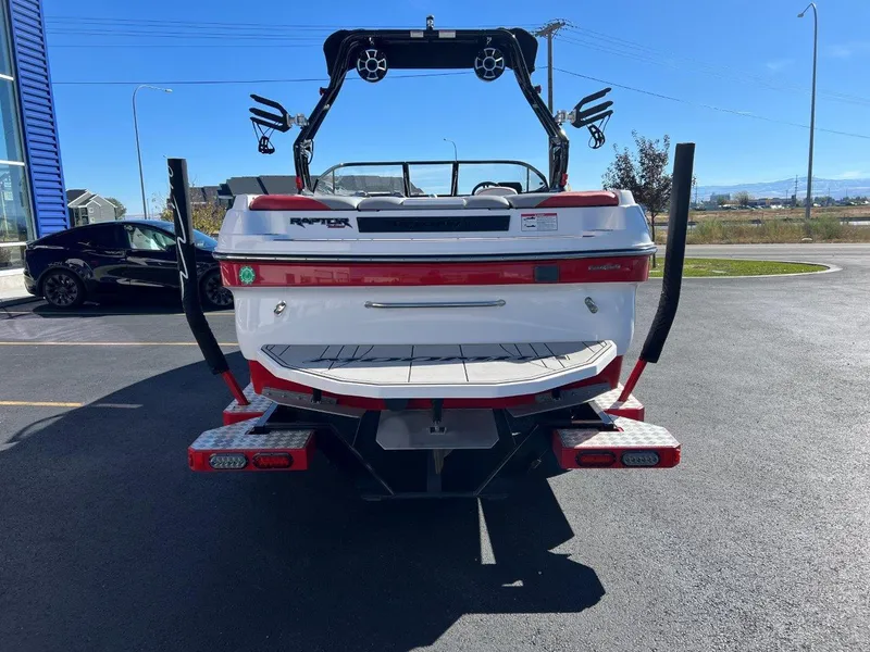 Slide: The Image of 2019 Moomba Mojo boat rear view in parking lot, showcasing wakeboard tower and swim platform. - 9