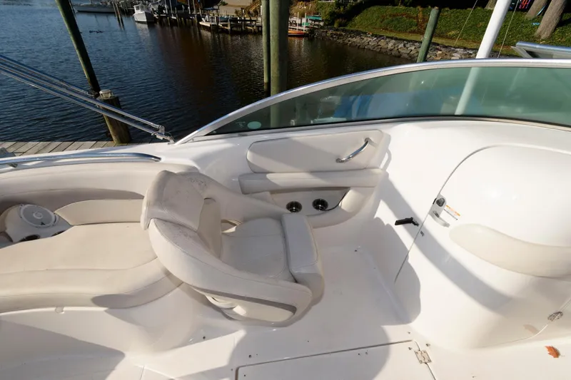 Slide: The Image of 2005 Chaparral Sunesta 274 boat interior with white seating and helm, docked by the water. - 8
