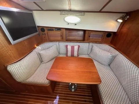 Slide: The Image of Cozy interior of 2003 Hinckley Talaria 44 FB with cushioned seating and wooden table. - 22
