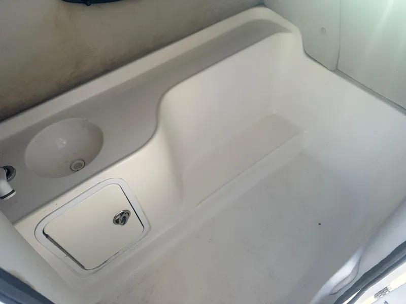Slide: The Image of Interior of a 2012 Godfrey Hurricane 237 boat, featuring a white sink and storage compartment. - 12