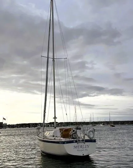 Slide: The Image of 1979 O'Day 28 sailboat named "Merlin" on calm waters under cloudy sky. - 2