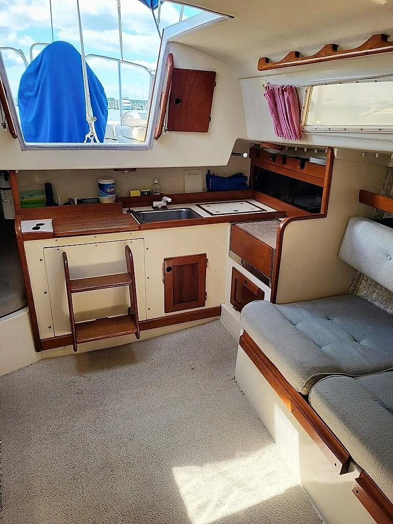 Slide: The Image of 1979 O'Day 28 sailboat interior with kitchenette, seating, and window view. - 34
