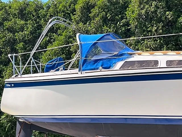 Slide: The Image of 1979 O'Day 28 sailboat with blue canopy, docked near lush green trees. - 5