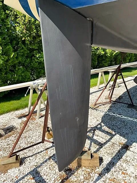 Slide: The Image of 1979 O'Day 28 sailboat keel on a gravel surface with green foliage background. - 7